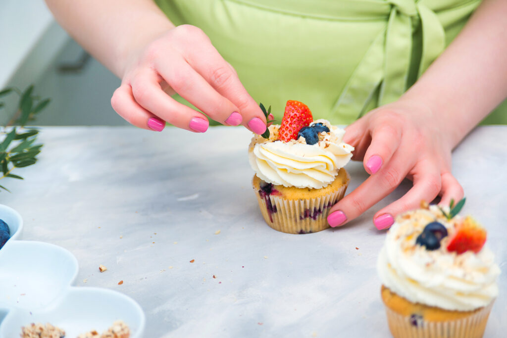 maos-femininas-finalizando-receita-de-cupcakes-e-doces-em-bancada-tendencias