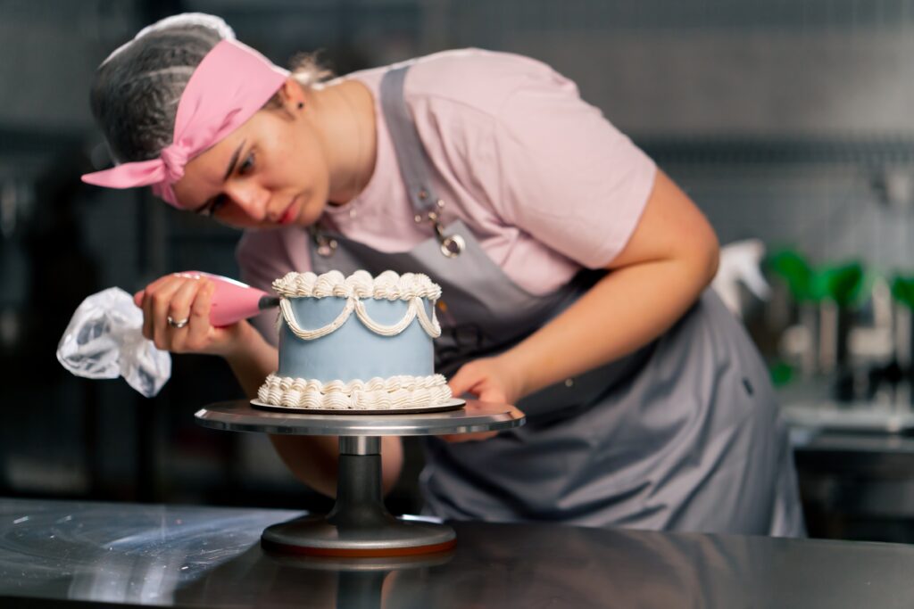 confeiteira-em-cozinha-confeitando-um-bolo-com-itens-de-confeitaria
